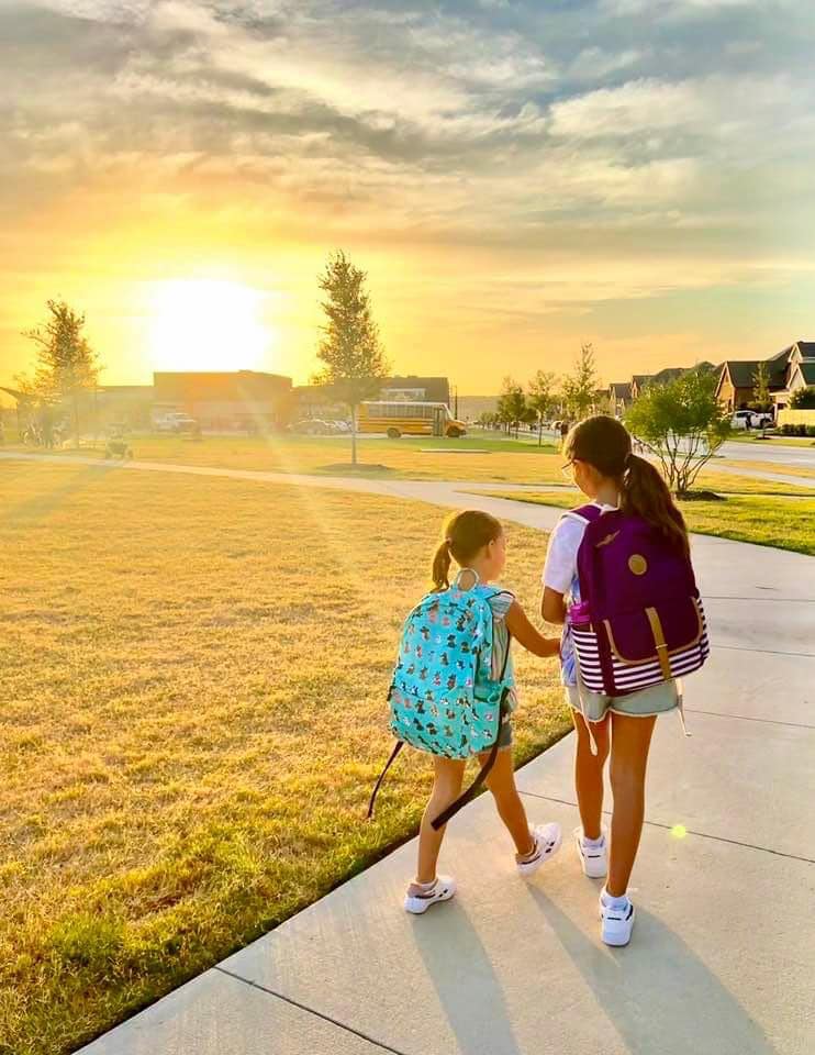 Two young girls walking to the school bus