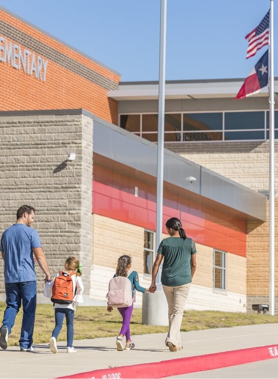 A mother and father walking their two daughters to the elementary school in Bluewood