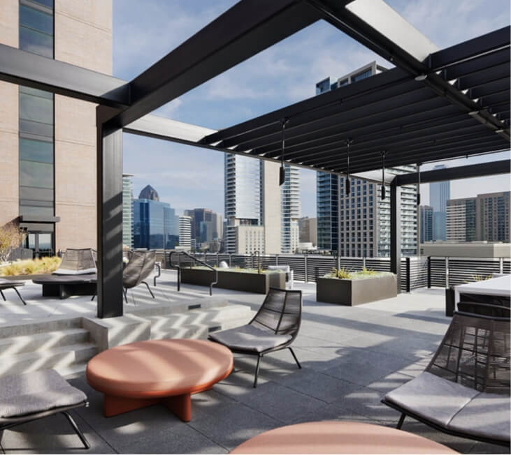 A rooftop terrace with chairs, tables and plantings overlooking the Dallas skyline