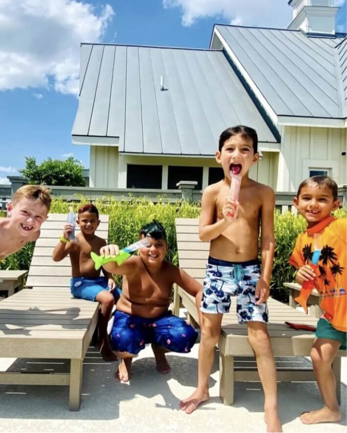 Five young boys eating popsicles by the pool at Pecan Square
