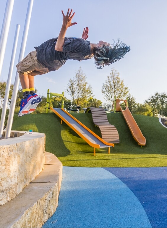 A boy doing a backflip in the park at Union Park