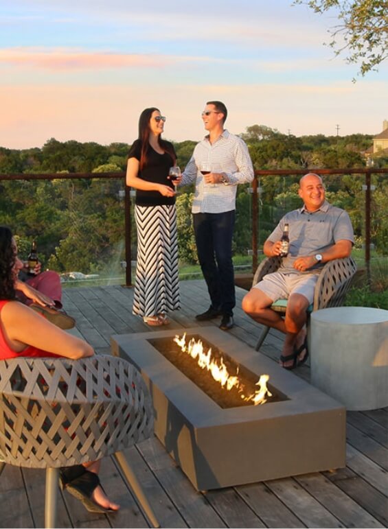 A group of people enjoying beverages around the firepit at Wolf Ranch