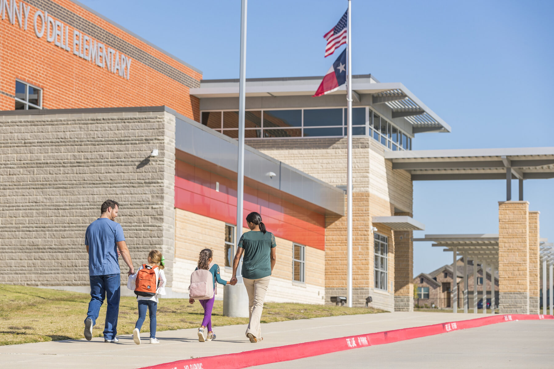 A mother and father walking their two daughters to the elementary school in Bluewood