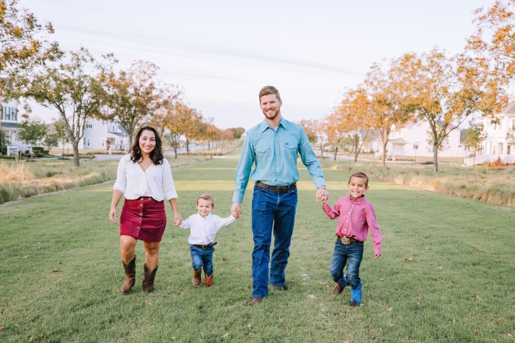 A young family walking along a grass walkway in Pecan Square