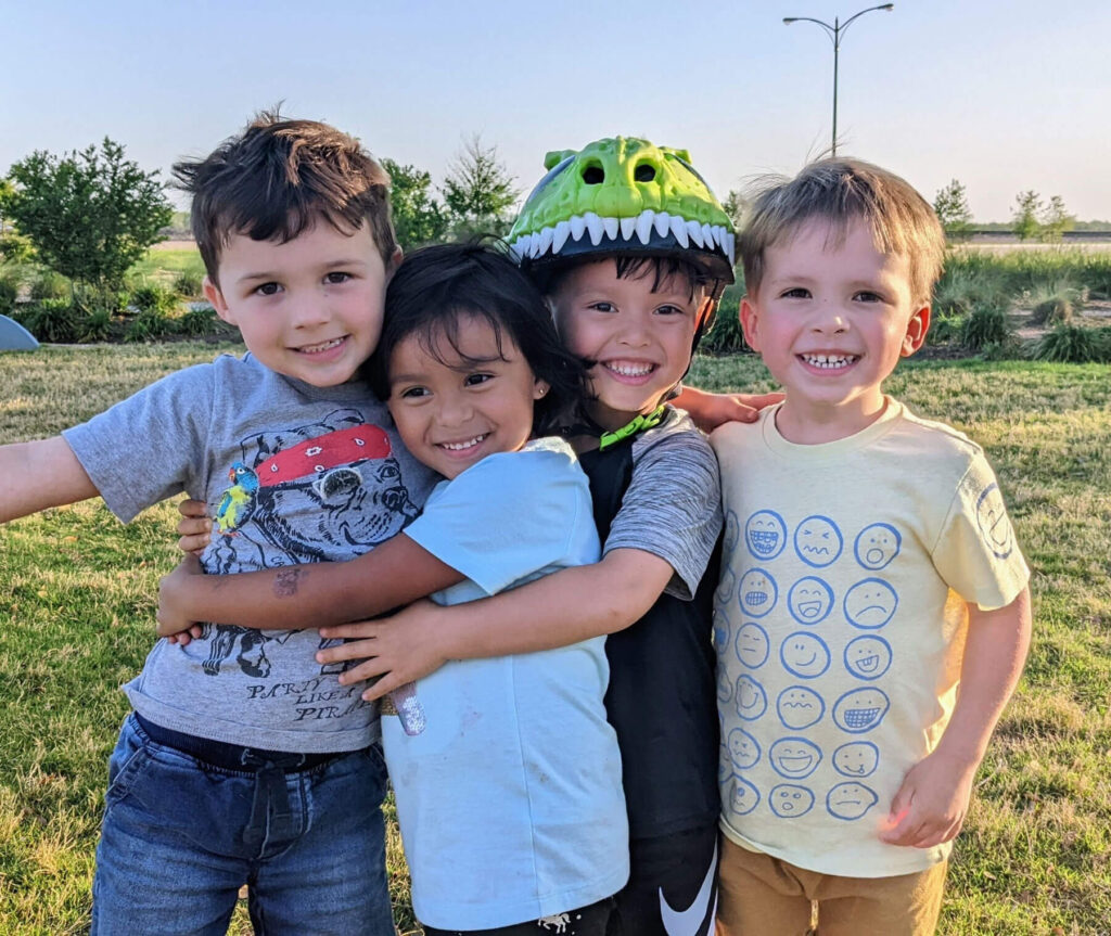 Four young boys hugging and smiling at the camera