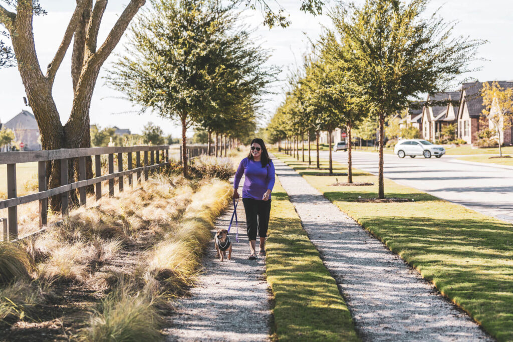 A woman walking her dog along a gravel path at a Lifestyle by Hillwood community