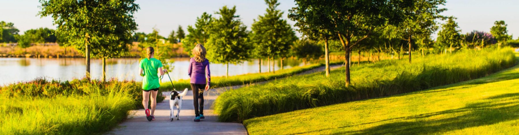 Two women walking their dog on a trail at a Lifestyle by Hillwood community