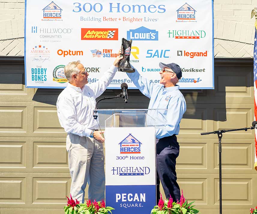 Ross Perot Jr. and another person at a podium celebrating the building of 300 homes for veterans